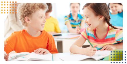 a young girl and boy sitting together in a classroom