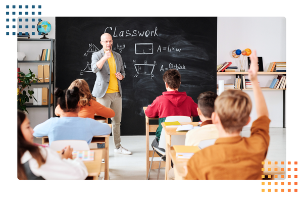 teacher stands at the front of a middle school classroom with a math problem on the chalkboard behind