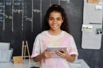 female student holding a tablet while smiling at the camera