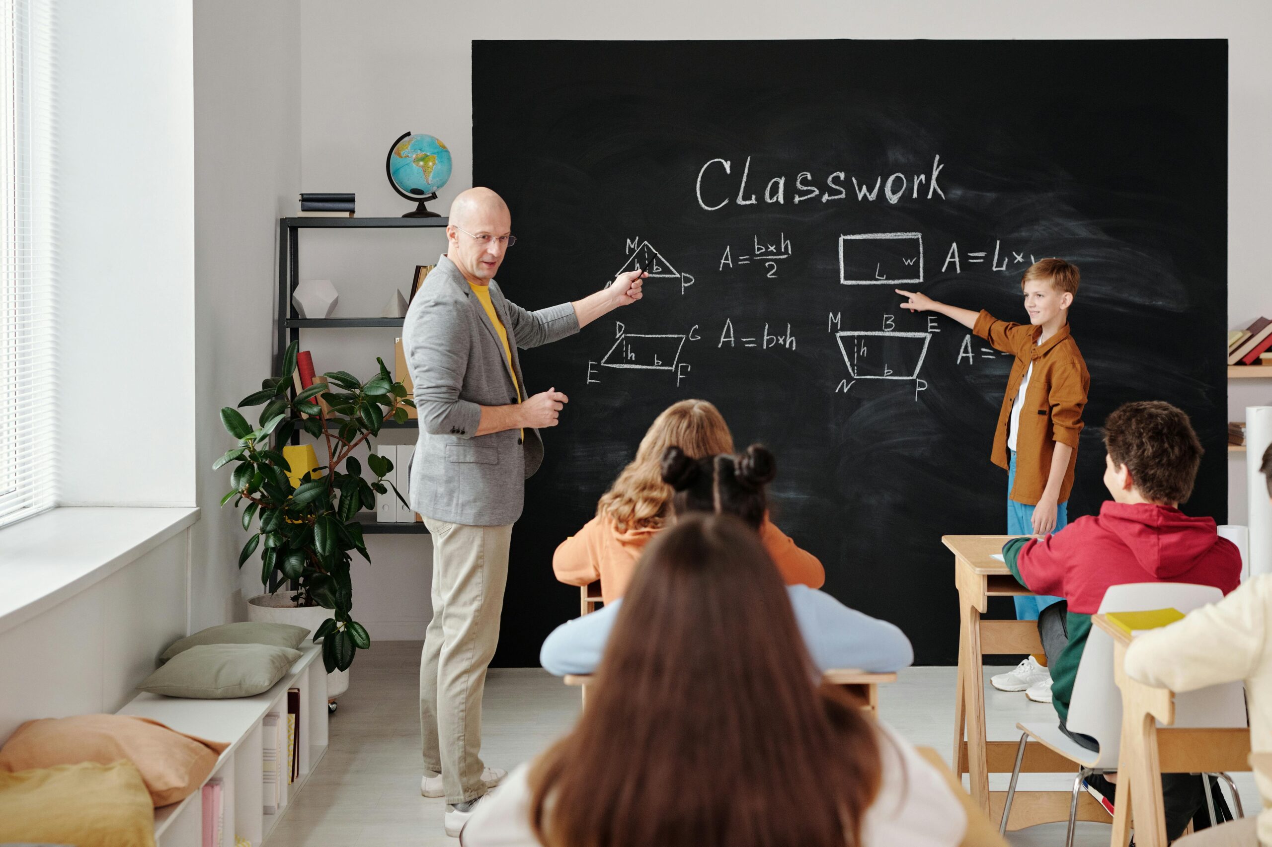 male teacher and male student working on a math problem on the chalkboard in front of the class